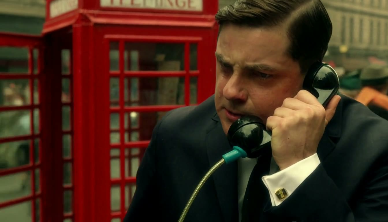 MiniMax H3 AI video example showing a man in a suit is passionately speaking into a vintage telephone booth in a bustling urban setting