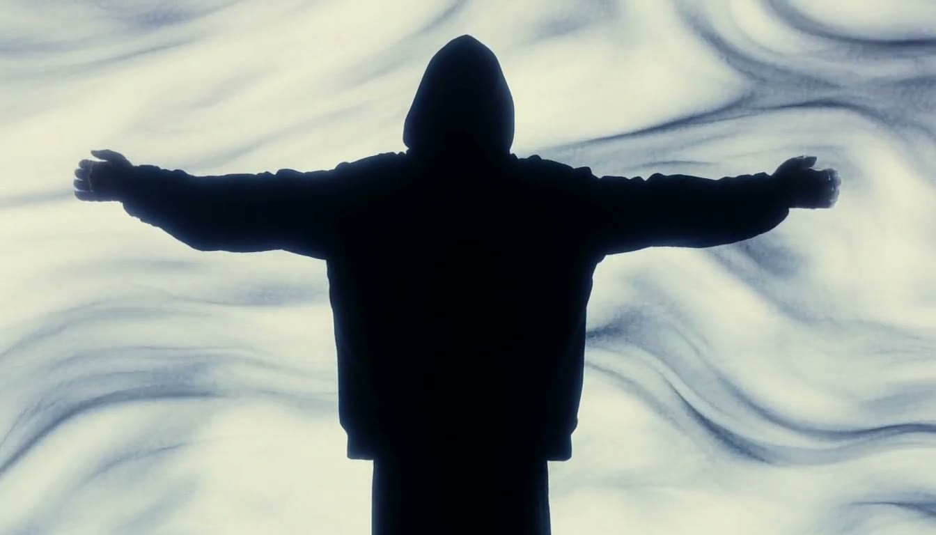 MiniMax H3 AI video example showing a person in a black hoodie with a swirling background transitions to wearing a bright green bomber jacket and carrying a suitcase in a dimly lit environment